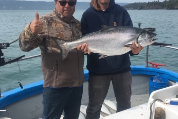 a man holding a fish on a boat in the water